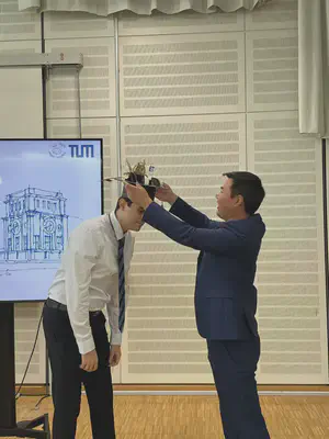 Kang places the doctoral hat, crafted by the team, on Ali